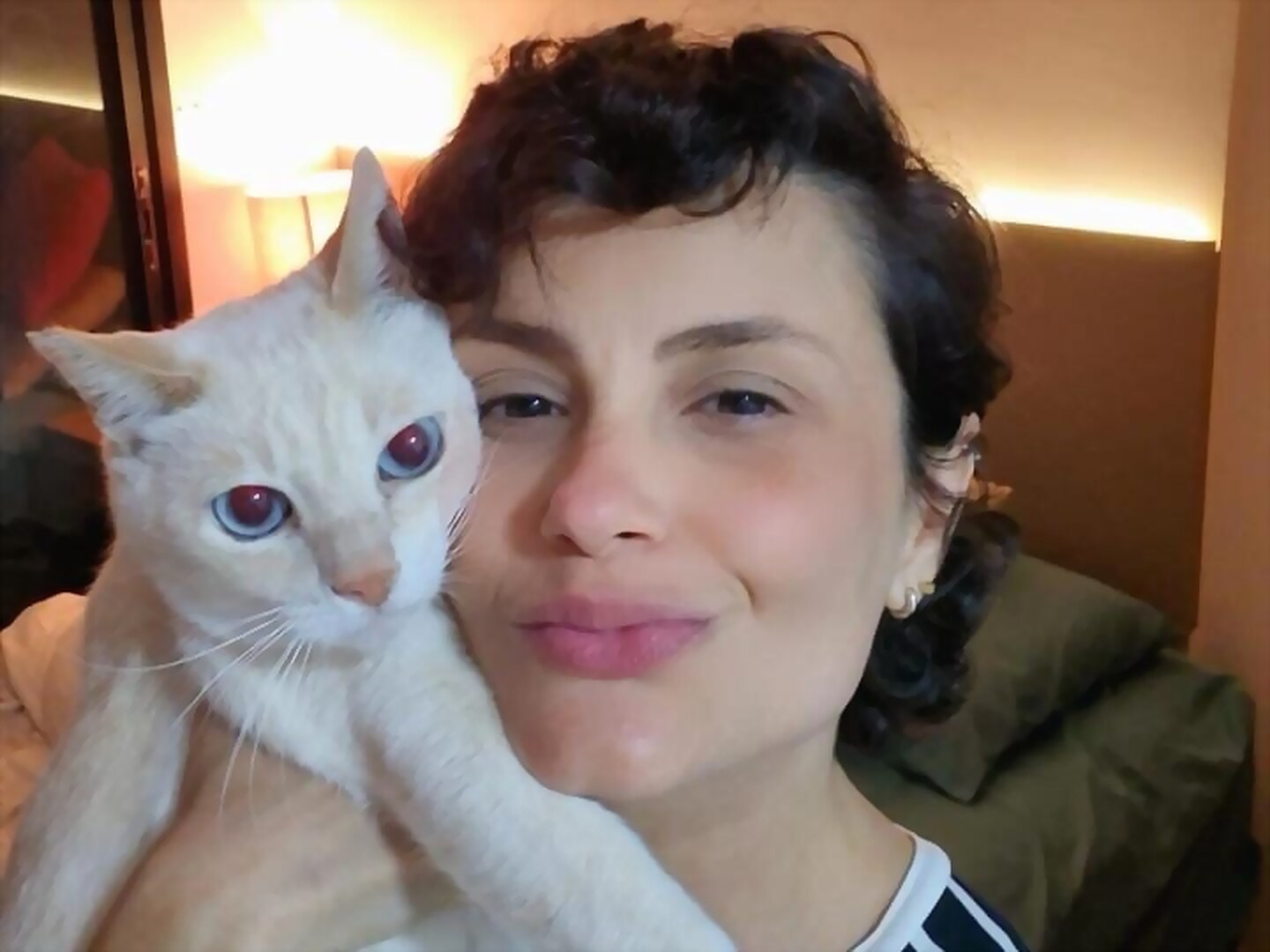 Tutora com seu gato branco no colo, em casa